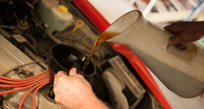 filling engine oil using funnel during general car service safety inspection at nambour car mechanic centre